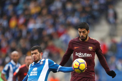 Luis Suárez controla el balón junto a Aarón Martín, del Espanyol.