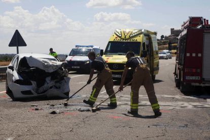Dos bombers, treballant al lloc de l’accident al costat del cotxe en el qual viatjava la víctima mortal.