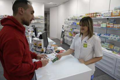 Una empleada de una farmacia en Balàfia vende un medicamento a un cliente.