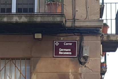 Una placa con el nombre tachado ayer por la mañana en la calle Germans Recasens y, a la derecha, después de ser limpiada.