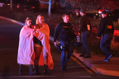 Dues dones embolicades en un llençol abandonen l'àrea del tiroteig a prop del bar Borderline a la localitat de Thousand Oaks, Califòrnia, Estats Units.
