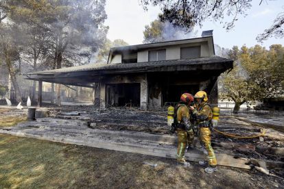 Dos bomberos hablan ante una de las viviendas afectadas por el incendio en la zona de la Marxuqera.
