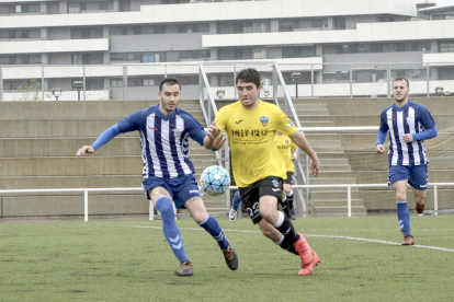 Un jugador del Lleida B con el balón controlado intenta irse por velocidad de un contrario.