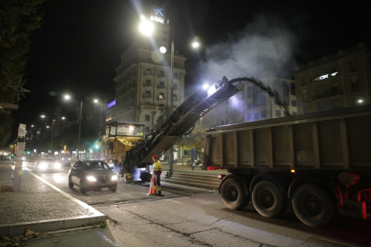 Una máquina retira el asfalto de avenida de Madrid mientras pasan dos vehículos por el carril abierto aún al tráfico, ayer por la noche. 