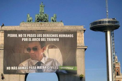 Greenpeace exige a Sánchez el fin de la venta de armas con un meme gigante en el Arco de Triunfo.