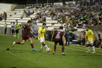 Pedro Martín intenta superar amb una passada la pressió de dos futbolistes del Compostel·la.