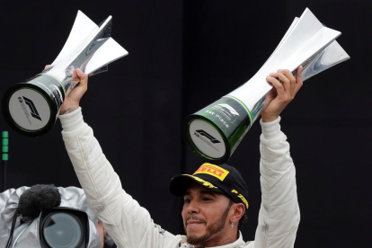 Lewis Hamilton, celebrando el triunfo en el podio con los trofeos.