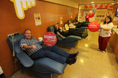 Los donantes del Arnau de Vilanova muestran sus packs de experiencias mientras donan sangre.