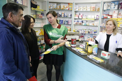 Una voluntaria informa sobre la campaña de recogida de medicamentos en una farmacia de Ronda.