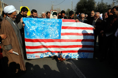 Un grupo de hombres quema una bandera estadounidense durante una protesta en Irán.