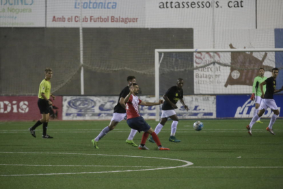 Un jugador del Balaguer desplaça la pilota davant la mirada de diversos futbolistes del Térmens. 