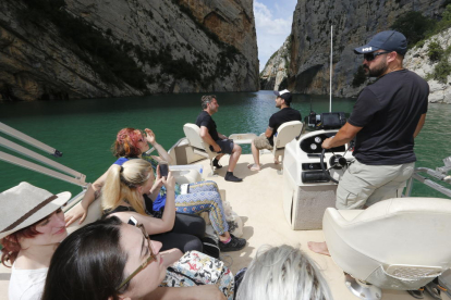 Turistas surcando el congosto de Mont-rebei ayer por la tarde.  En la foto inferior a la derecha el barco pasando por debajo de la pasarela peatonal sobre el río.