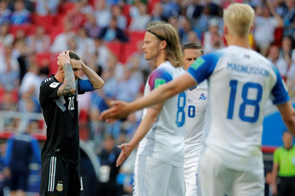 Messi se toca la cara mientras espera que le llegue el balón ante la vigilancia de Bjarnason.