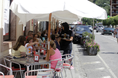 Una camarera sirve las mesas de una terraza llena de clientes en Sort. 