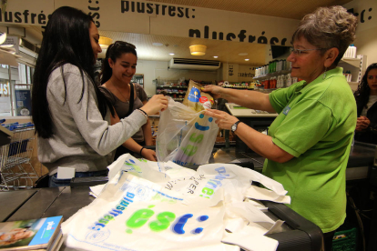 Una empleada d’un supermercat de l’Eix Comercial col·loca productes en una bossa de plàstic.