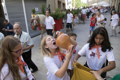 Arriba, una chica bebiendo del agua de Sant Magí en Cervera. A la derecha, la alcaldesa de Tàrrega recibiendo el cántaro conmemorativo.