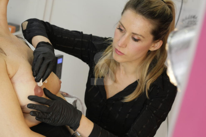 Una tatuadora realiza micropigmentación a una afectada por cáncer de mama.