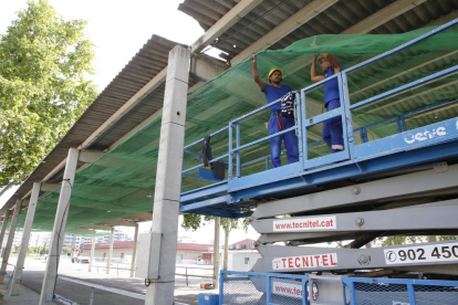 Operarios instalan un toldo provisional debajo del fibrocemento.