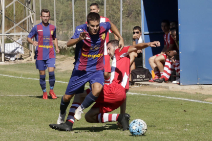 Un jugador del equipo local avanza con el balón ante la entrada de un rival.