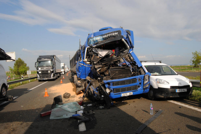 Imagen de uno de los camiones implicados y al lado, la cola de vehículos.