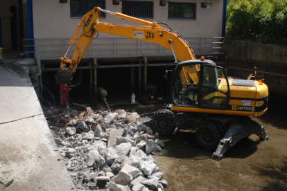 Una màquina excavadora retira el llot acumulat al canal d’aigües tranquil·les.