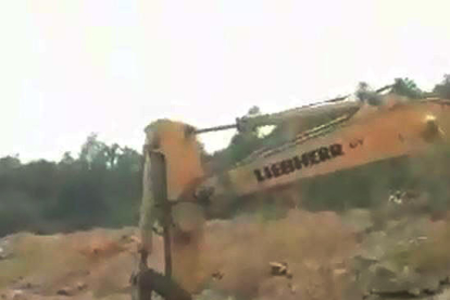 Una máquina trabajando al lado de un muro de piedra seca.