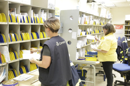 Dos treballadores classifiquen les cartes a les oficines de Correus al carrer Segòvia de Lleida.