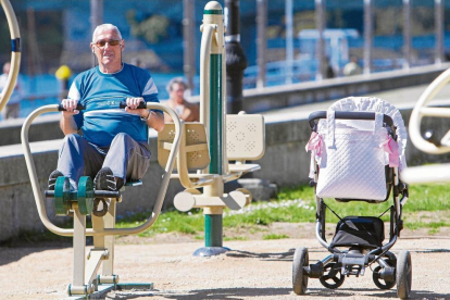Un pensionista fa exercici en un parc públic mentre cuida la néta