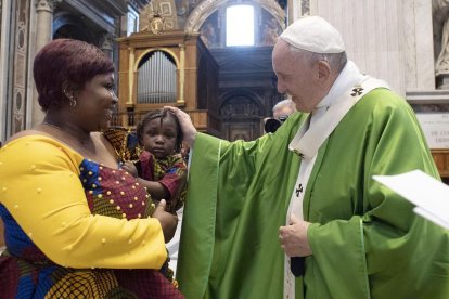 El Papa saluda a una inmigrante junto a su hijo tras la misa.