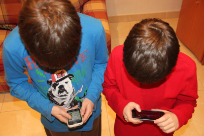 Imagen de dos niños jugando con el teléfono móvil en casa. 