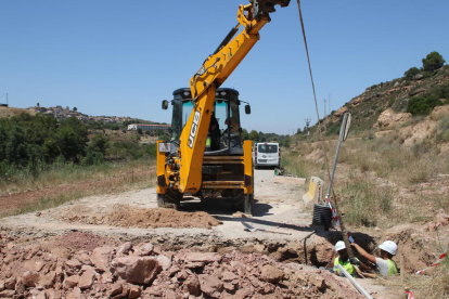 Els operaris treballen ara en el drenatge d’un dels camins, prop de la presa i del municipi (esquerra).