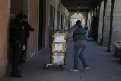 Un agente de la Guardia Civil saca cajas con documentos del edificio del ayuntamiento de Almacelles.