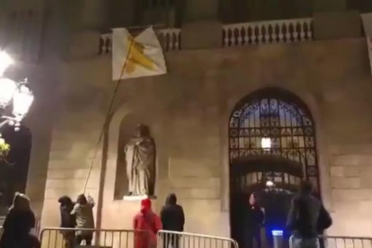 Un grup de persones despenja el llaç groc de l'ajuntament de Barcelona