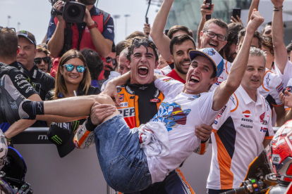 Marc Márquez celebra eufórico el título mundial conquistado por su hermano Àlex al que levata en brazos.
