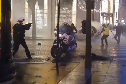 Un gendarme francés sacó su arma reglamentaria ante los manifestantes.