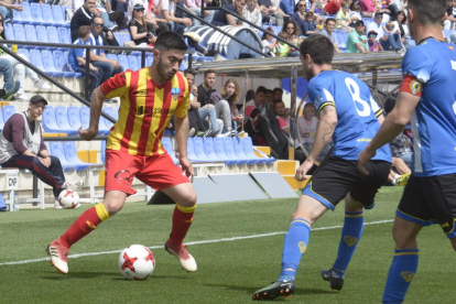 Un jugador del Lleida coduce el balón ante dos rivales.