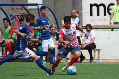 Genís conduce un balón ante la oposición de dos jugadores rivales.