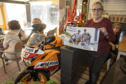 Elvira Colom, de la pastisseria Cal Colom, mostra un pòster al costat de la rèplica de la moto de Marc.