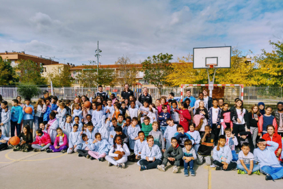 Los alumnos del IE Torre Queralt, junto a los jugadores del Força Lleida durante la visita del martes en el patio del centro educativo.