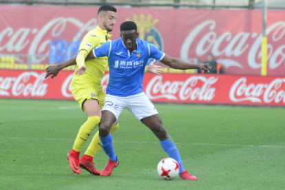 Trilles intenta superar la entrada de un jugador del Villarreal B, en una acción del partido de ayer.