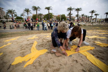 Dos joves col·loquen creus de tela grogues a la platja de Mataró, en una iniciativa del Comitè de Defensa de la República.