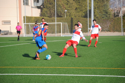 Un jugador del Térmens controla la pilota davant la presència de diversos defenses locals durant una acció del partit.