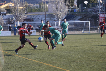 Un jugador de l’EFAC Almacelles pugna amb un del Martinenc, amb diversos jugadors dels dos equips al fons.