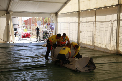 Personal del SEM plegando la carpa que instalaron en junio junto a Urgencias del Arnau y a la derecha, material para vallar la zona donde se construirá el anexo al hospital.