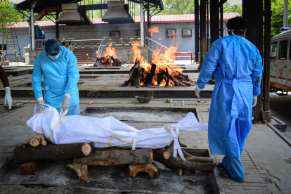 Dos operarios se disponen a quemar a el cuerpo de una víctimas del coronavirus en un crematorio en Nueva Delhi, India.