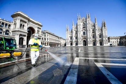 Un trabajador italiano efectua tareas de desinfección del suelo de la Piazza del Duomo de Milán.