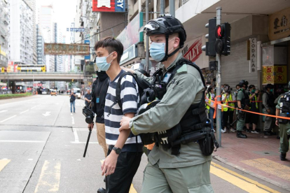 Agentes hongkoneses llevan detenido a uno de los manifestantes.