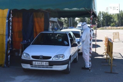 Empleats del sector sanitari realitzen proves PCR a diversos ciutadans des dels seus cotxes, aquest dimecres davant l'aparcament del camp de futbol Reino de León.