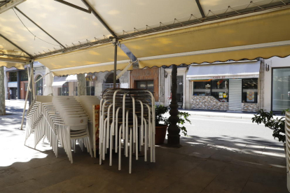 Sillas apiladas en la terraza de un bar cerrado en la Rambla Ferran de Lleida.