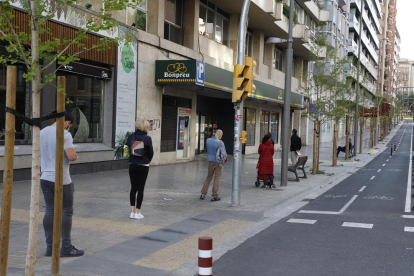 Ciudadanos haciendo cola manteniendo la distancia de seguridad delante de un supermercado en el centro urbano. 